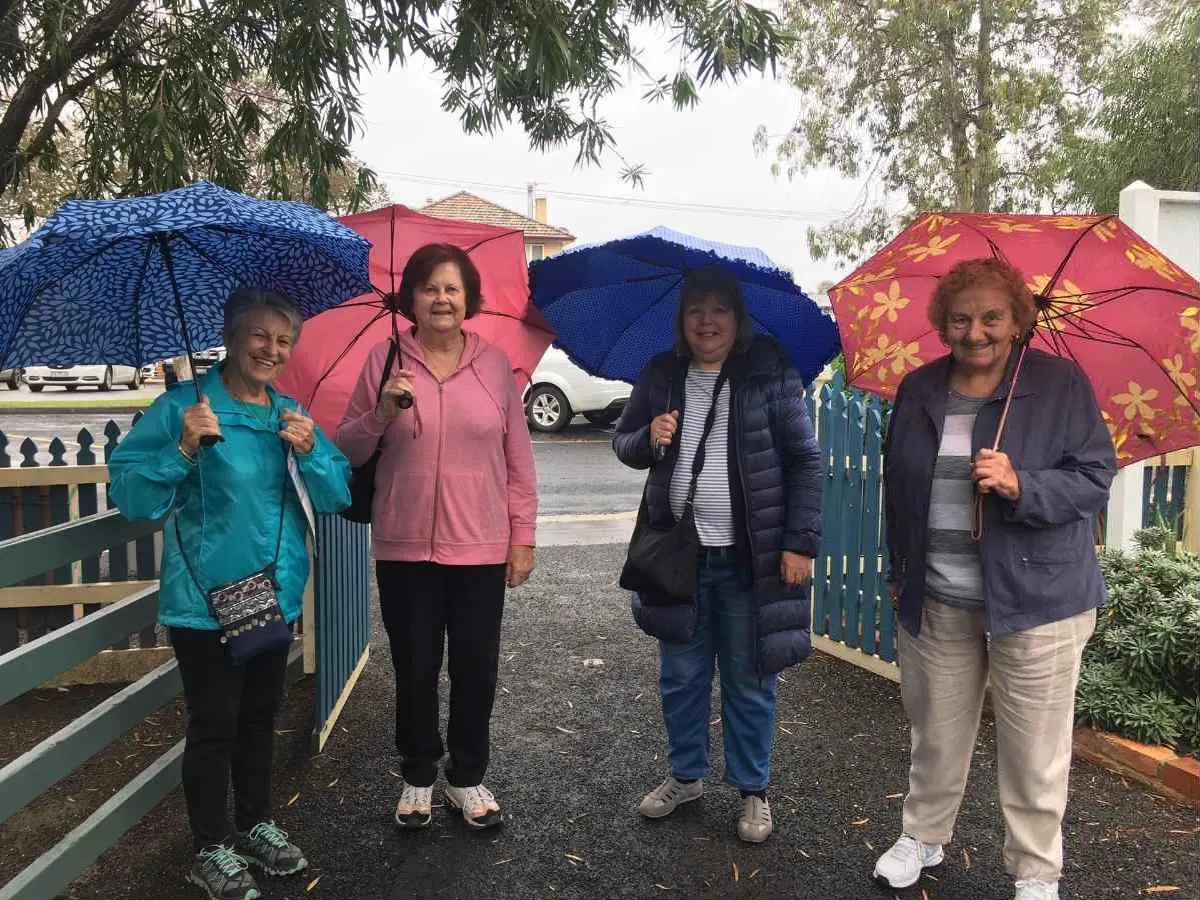 Four Hoofers walkers smiling under umbrellas on a rainy morning