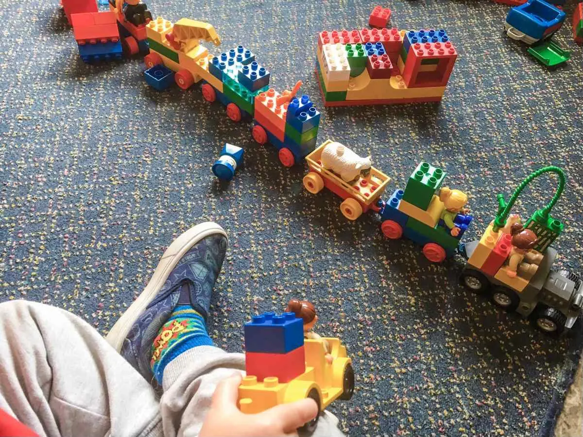 A child playing with a train of building blocks on the Kids House carpet